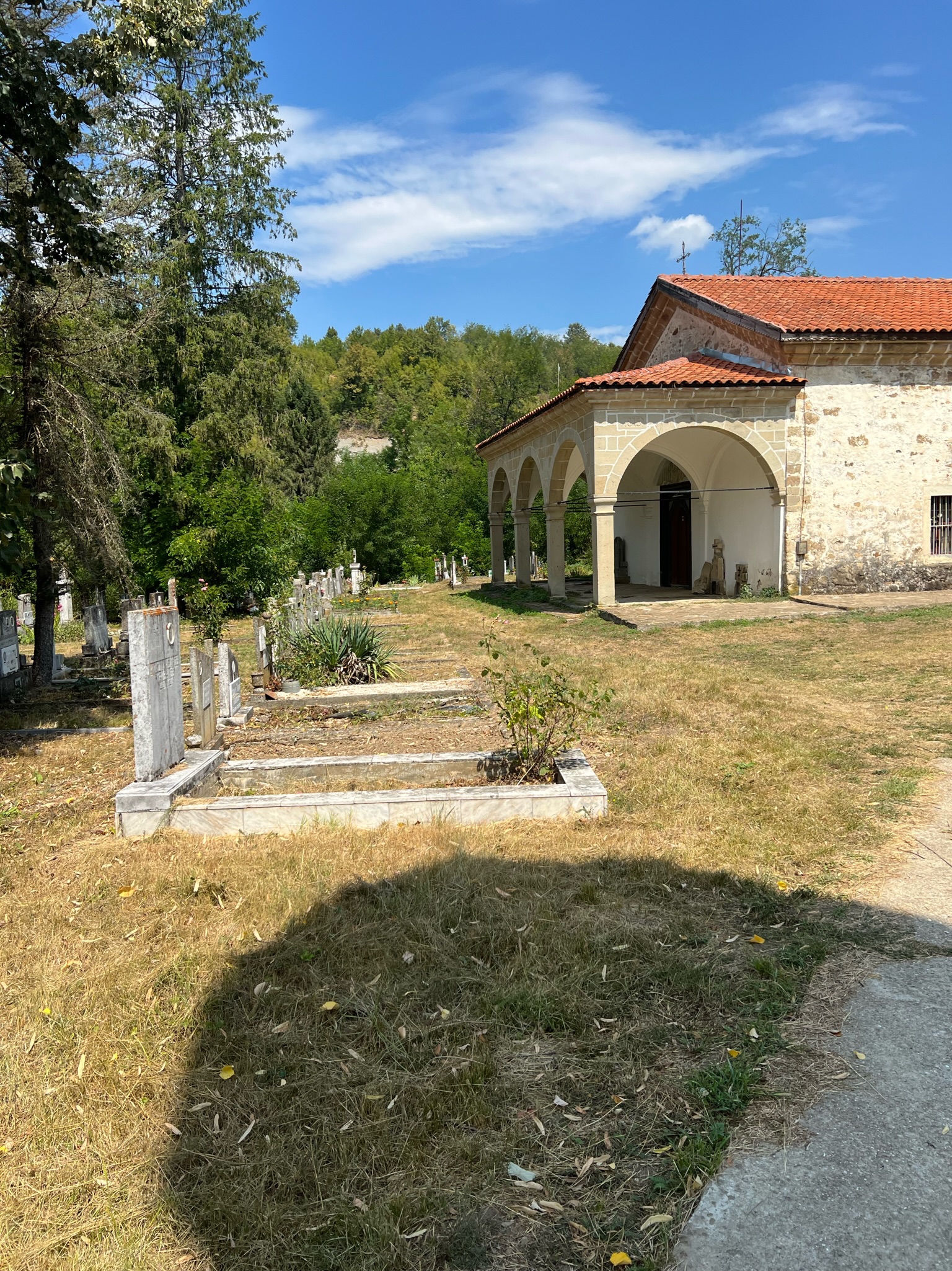 Old Bulgarian Orthodox monastery courtyard with arched portico and gravestones