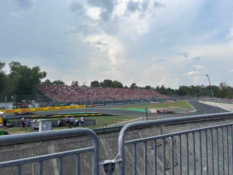 Monza circuit with cars racing past packed grandstands full of tifosi